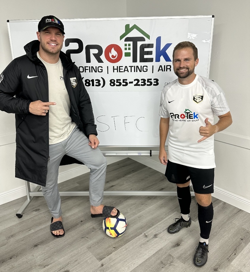 Protek Roofing, Heating, Air & Solar employee and South Tampa FC member posing in front of whiteboard with soccer ball